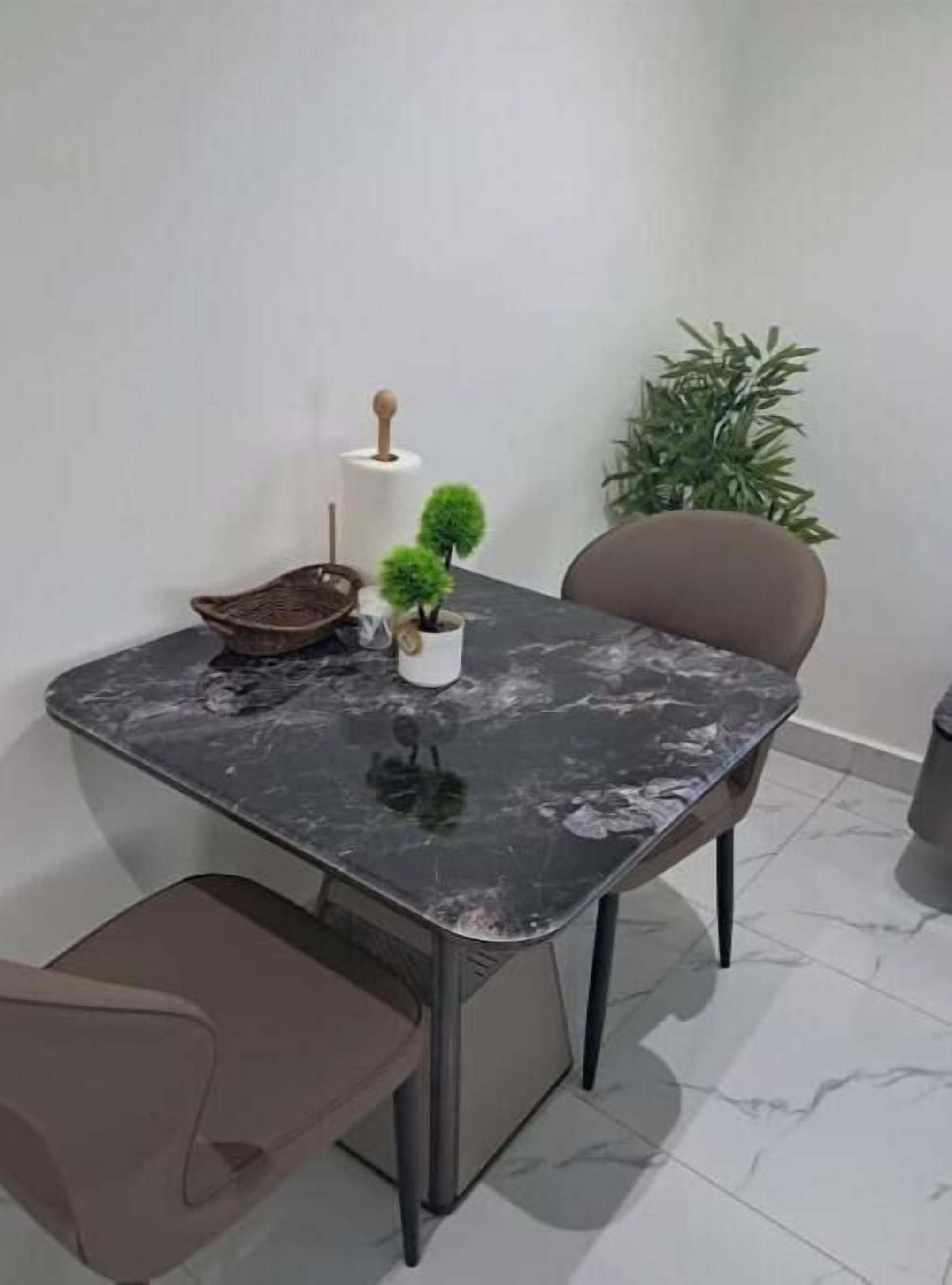Un coin repas comprenant une table en marbre, une chaise, une petite plante en pot et un objet fixé au mur.