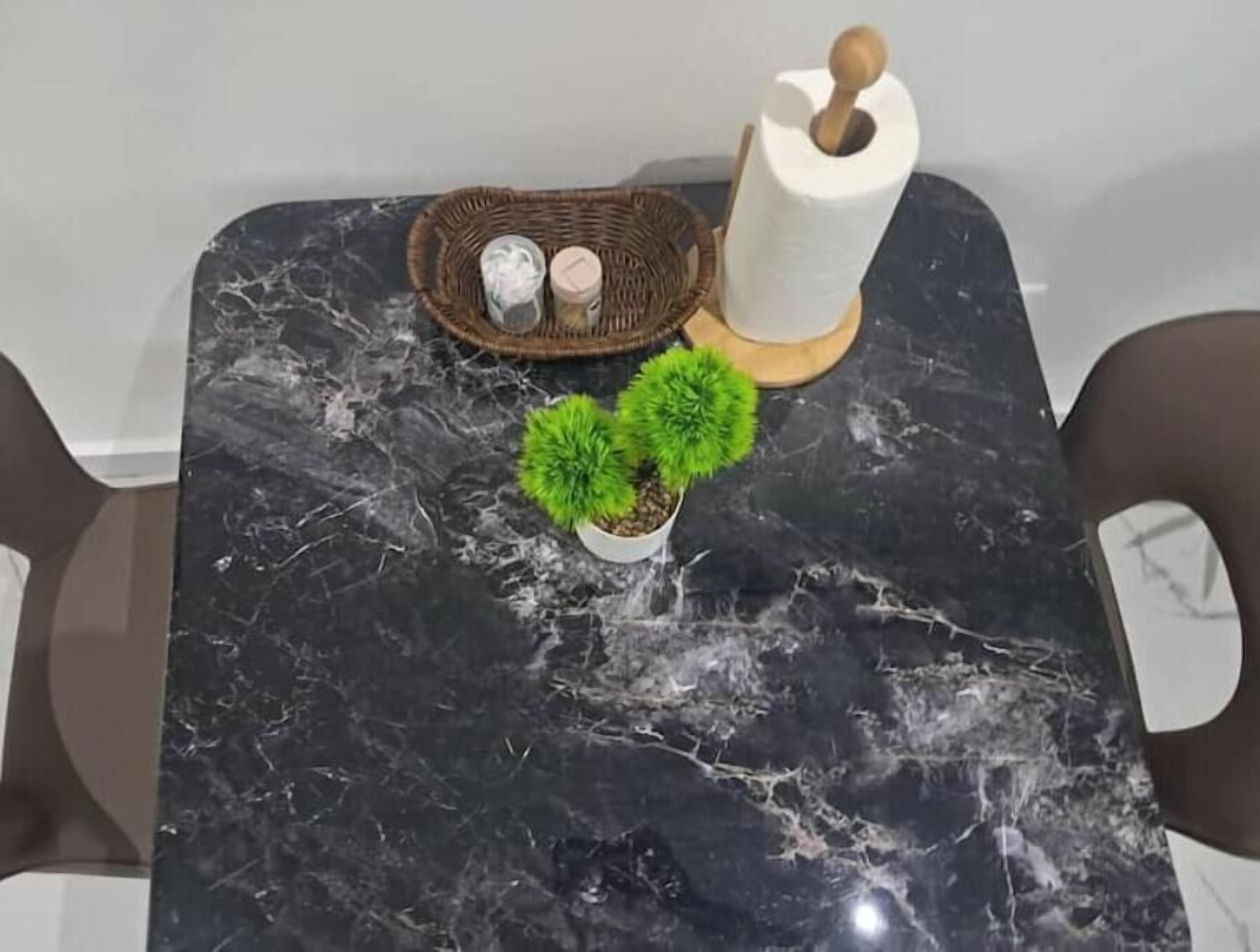 A marble table with a small potted plant, a wicker basket with items, and a roll of paper towels.