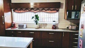 Una cocina con ventana, licuadora, tostadora y microondas.