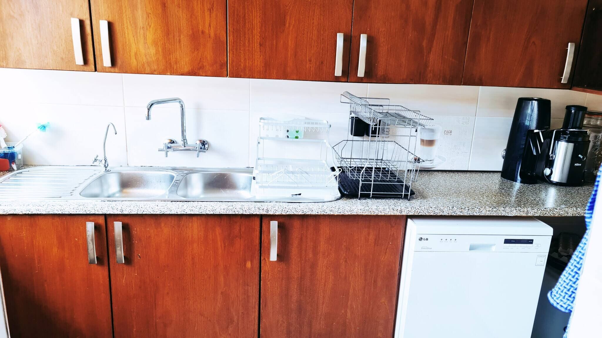 Eine Küche mit Holzausstattung, einem doppelten Waschbecken, einem Geschirrständer und einer Kaffeemaschine.