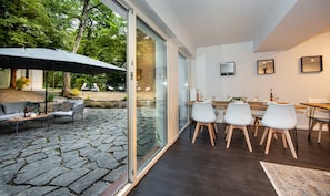 A modern interior with a dining area, a patio with outdoor seating, and a glass door leading to an outdoor space. - Bendorfer Stadl Whirlpool-sauna-billard-kicker (Bendorf)
