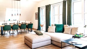A modern living room with a sofa, ottoman, and dining area with chairs. - Rheinsteig Chalet Whirlpool-sauna-billard-kicker (Bendorf)