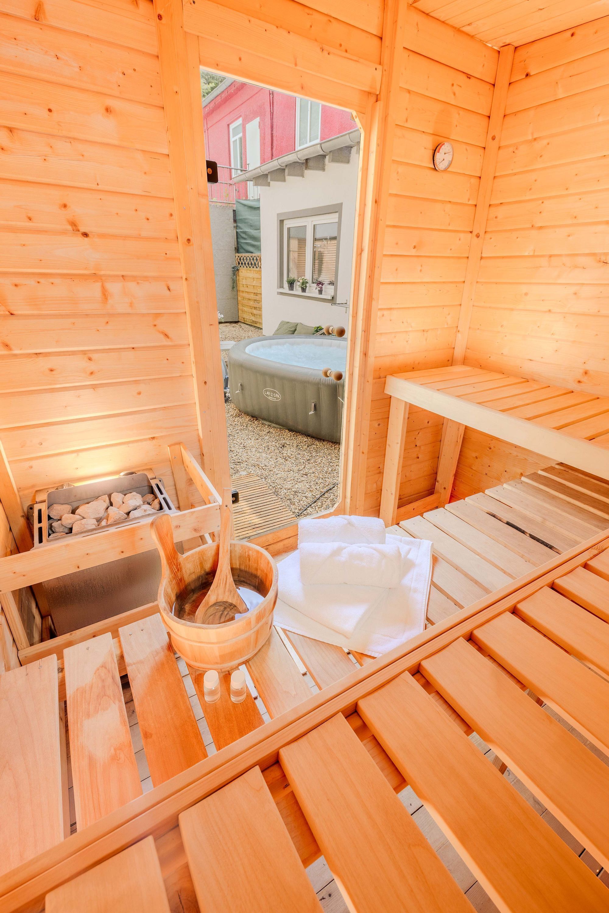 Una sala de sauna con bancos de madera, un balde de madera y una toalla blanca.