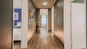 A hallway with a bed, a small table with a plant, and a door leading to another room. - Rheinsteig Chalet Whirlpool-sauna-billard-kicker (Bendorf)