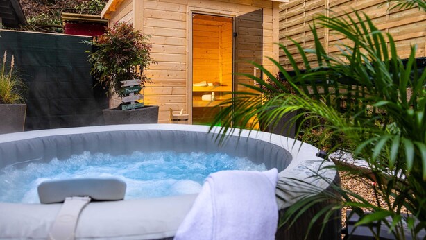 A hot tub with a wooden deck, a wooden sauna, and a garden area with plants. - Rheinsteig Chalet Whirlpool-sauna-billard-kicker (Bendorf)