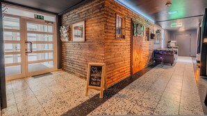 A wooden cabin-style interior with a reception desk, framed pictures, a chalkboard sign, and a plush armchair. - Rheinsteig Chalet Whirlpool-sauna-billard-kicker (Bendorf)