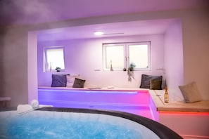 Un cuarto de spa con un jacuzzi, una zona de estar con vistas al cielo y una ventana con una planta.