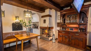Una mesa de comedor de madera con un banco, una chimenea y un televisor montado en la pared.
