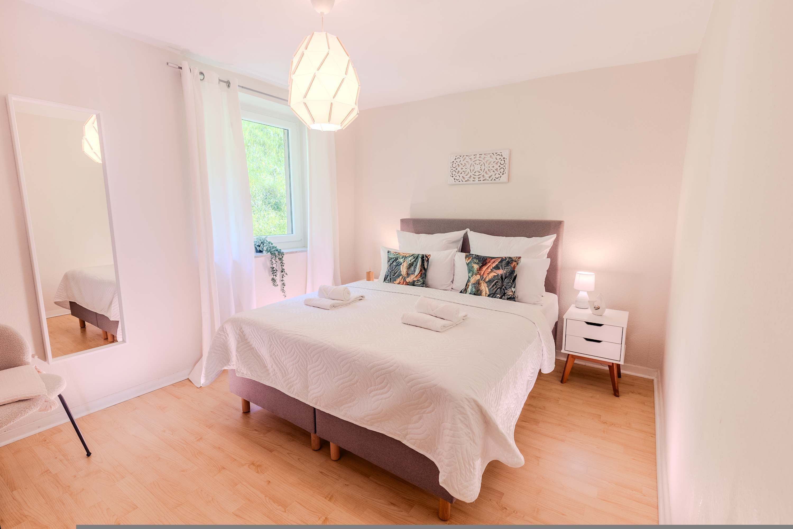 Une chambre à coucher avec un lit, une table de chevet et une fenêtre avec des rideaux.