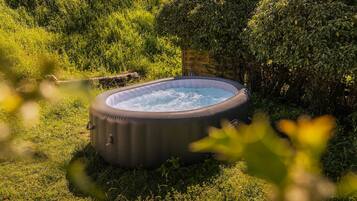 A hot tub in a grassy area with a wooden structure nearby.