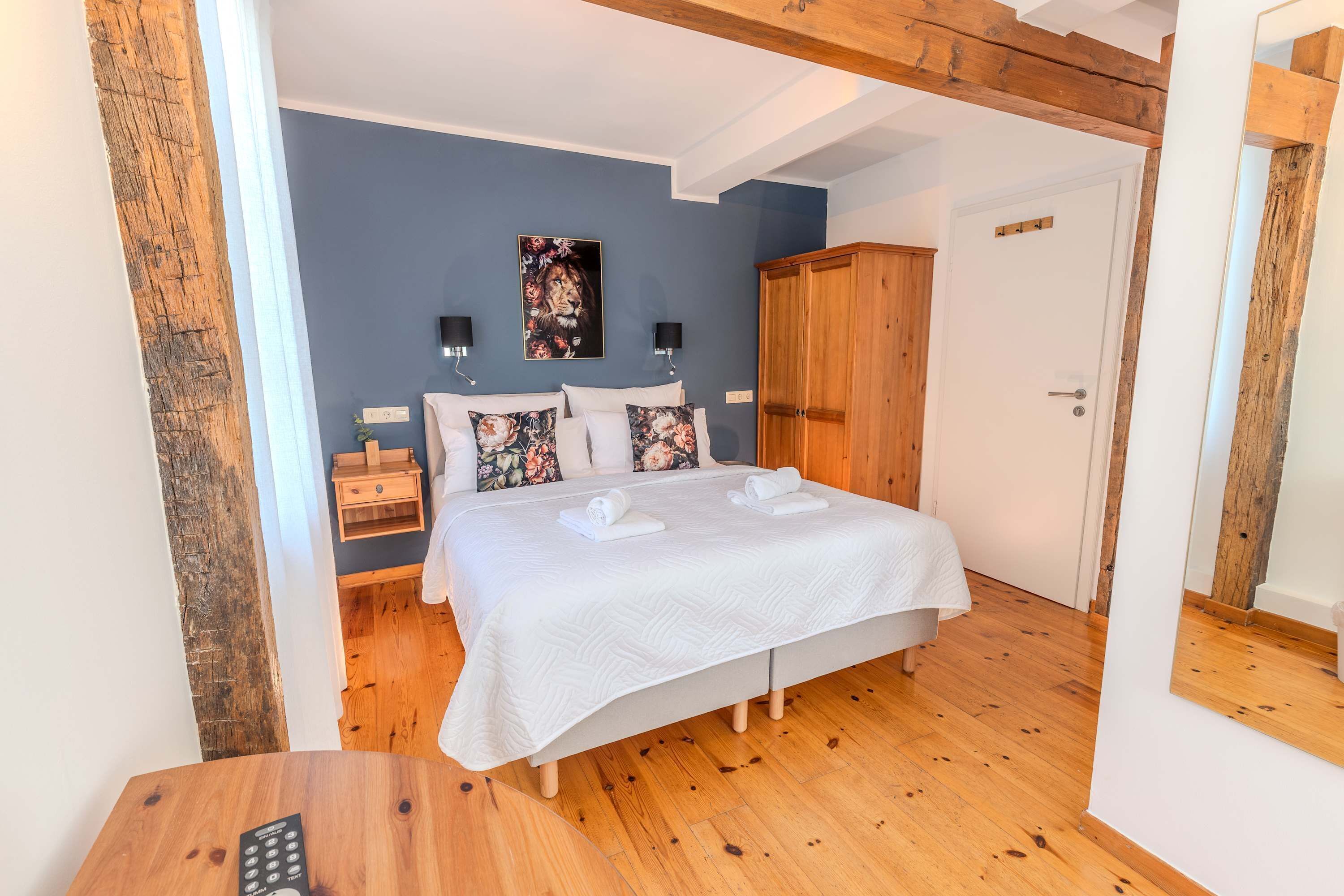A bedroom with a bed, bedside tables, a wardrobe, and a painting on the wall.