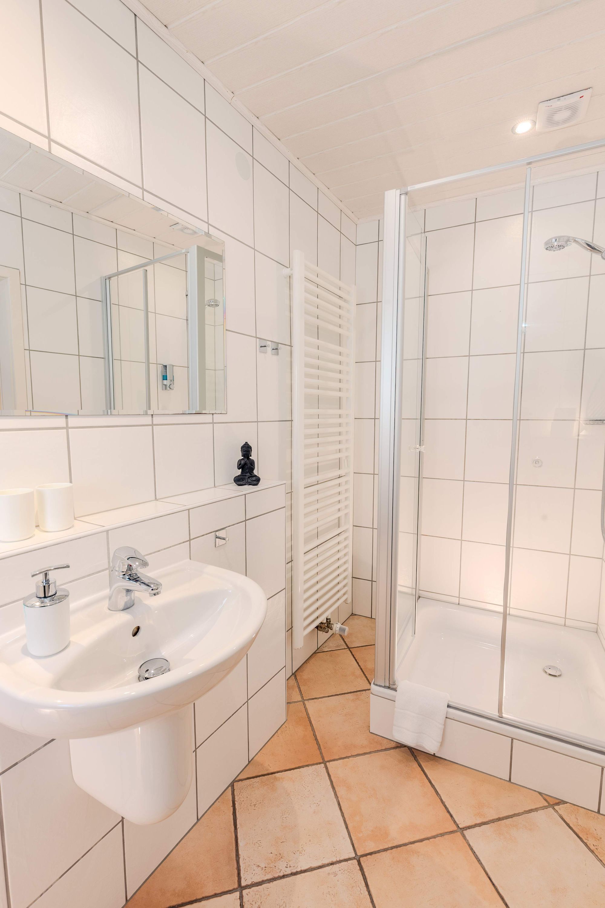 Une salle de bain équipée d’un lavabo, d’un miroir et d’une douche à parois en verre.