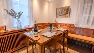 A dining area with a wooden table set for two, a bench, and a radiator.