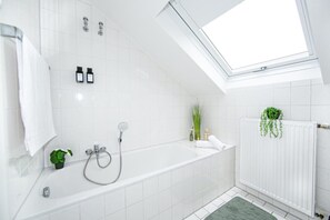 A modern bathroom with a skylight, a bathtub, a shower, and a radiator. - Stilvolle Wohnung mit Balkon in Horchheim (Koblenz)