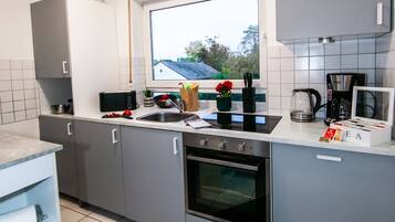 A modern kitchen with grey cabinets, a built-in oven, a window, and a view of the outdoors.