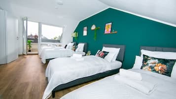 A hotel room with three beds, a large window, and a view of the outside.