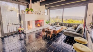 A modern living room with a fireplace, a sofa, a coffee table, and a balcony with a view. - Villa Panoramica Pool Sauna (Weitersburg)
