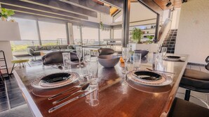 A modern kitchen with a large island, dining area, and a staircase leading to an upper level. - Villa Panoramica Pool Sauna (Weitersburg)