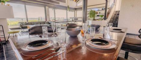 A modern kitchen with a large island, dining area, and a staircase leading to an upper level.