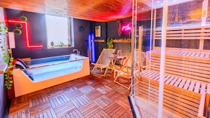 A wooden interior with a large bathtub, a wooden deck, and a glass wall. - Villa Bueckeberg Game-room and Wellness (Luhden)