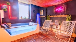 A modern spa room with a large bathtub, wooden flooring, and a neon sign. - Villa Bueckeberg Game-room and Wellness (Luhden)