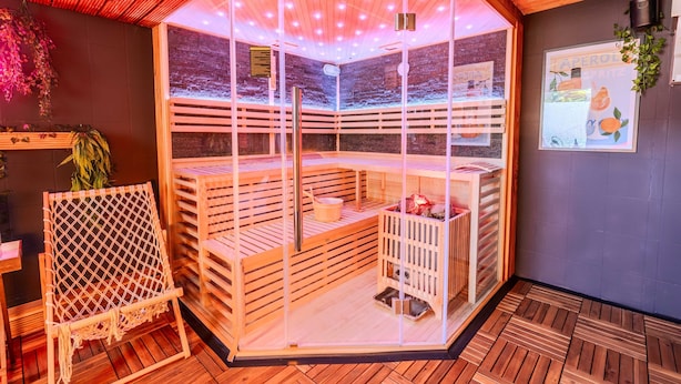 A sauna with wooden slats, a bench, and a hanging plant. - Villa Bueckeberg Game-room and Wellness (Luhden)