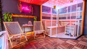 A wooden deck with two hammocks, a seating area, and a sauna visible through a glass partition. - Villa Bueckeberg Game-room and Wellness (Luhden)