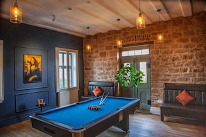A pool table in a room with stone walls, a bench, and a door. - Haltestelle Glauburg - Sauna Whirlpool (Glauburg)