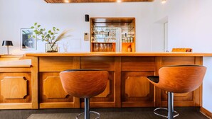 A wooden bar area with two stools, a glass display case, and pendant lighting. - Whirlpool Sauna Kino Villa Klosterschenke (Sankt Goarshausen)
