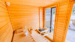 A wooden sauna room with a bench, a bucket, and a small table with a fire. - Whirlpool Sauna Kino Villa Klosterschenke (Sankt Goarshausen)