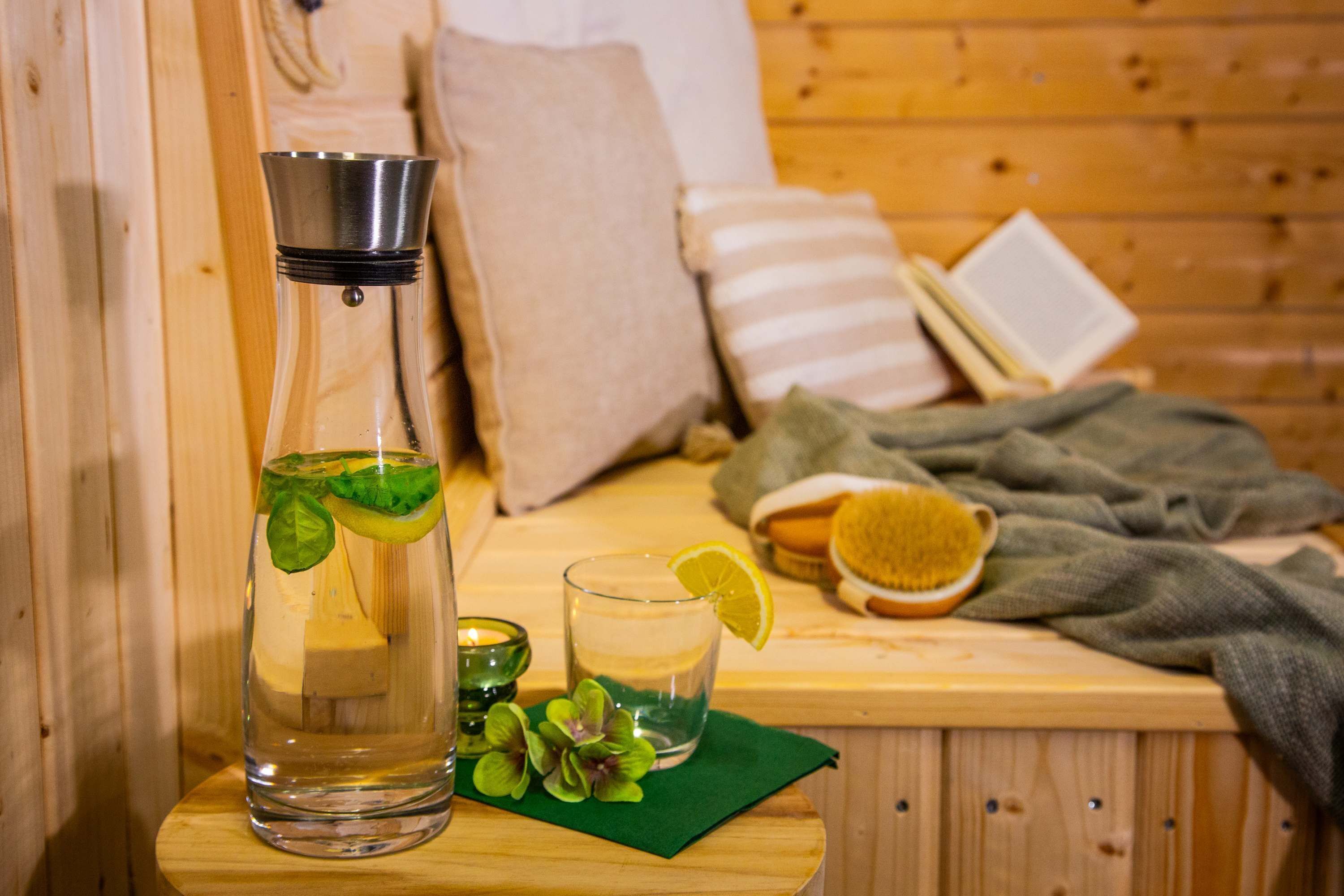 A wooden room with a bed, pillows, a book, a glass of water, a bottle, and a brush.