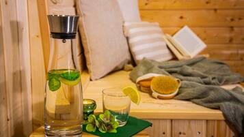 A wooden room with a bed, pillows, a book, a glass of water, a bottle, and a brush.
