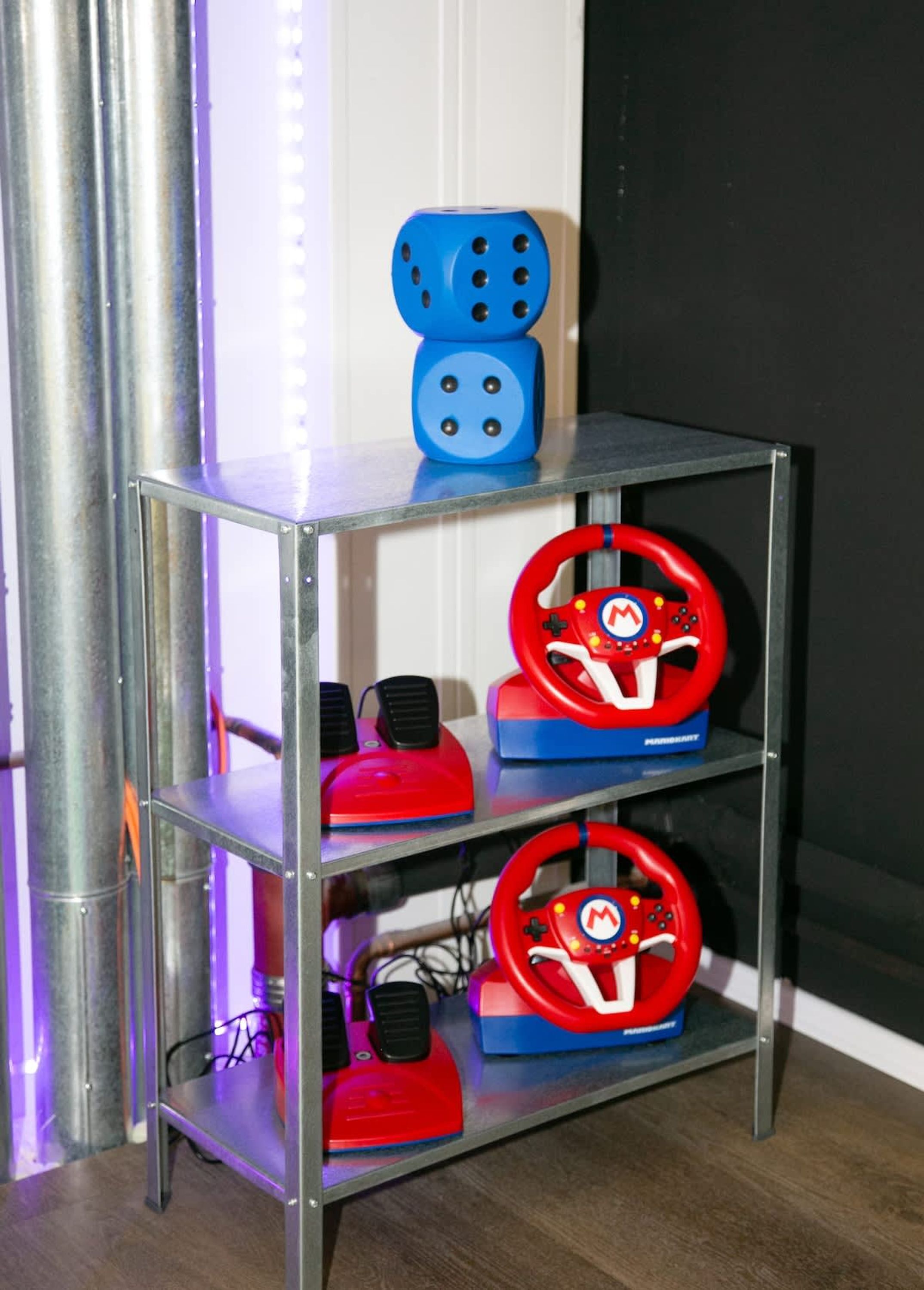 A metal shelf with three racing wheels and a blue dice on top.