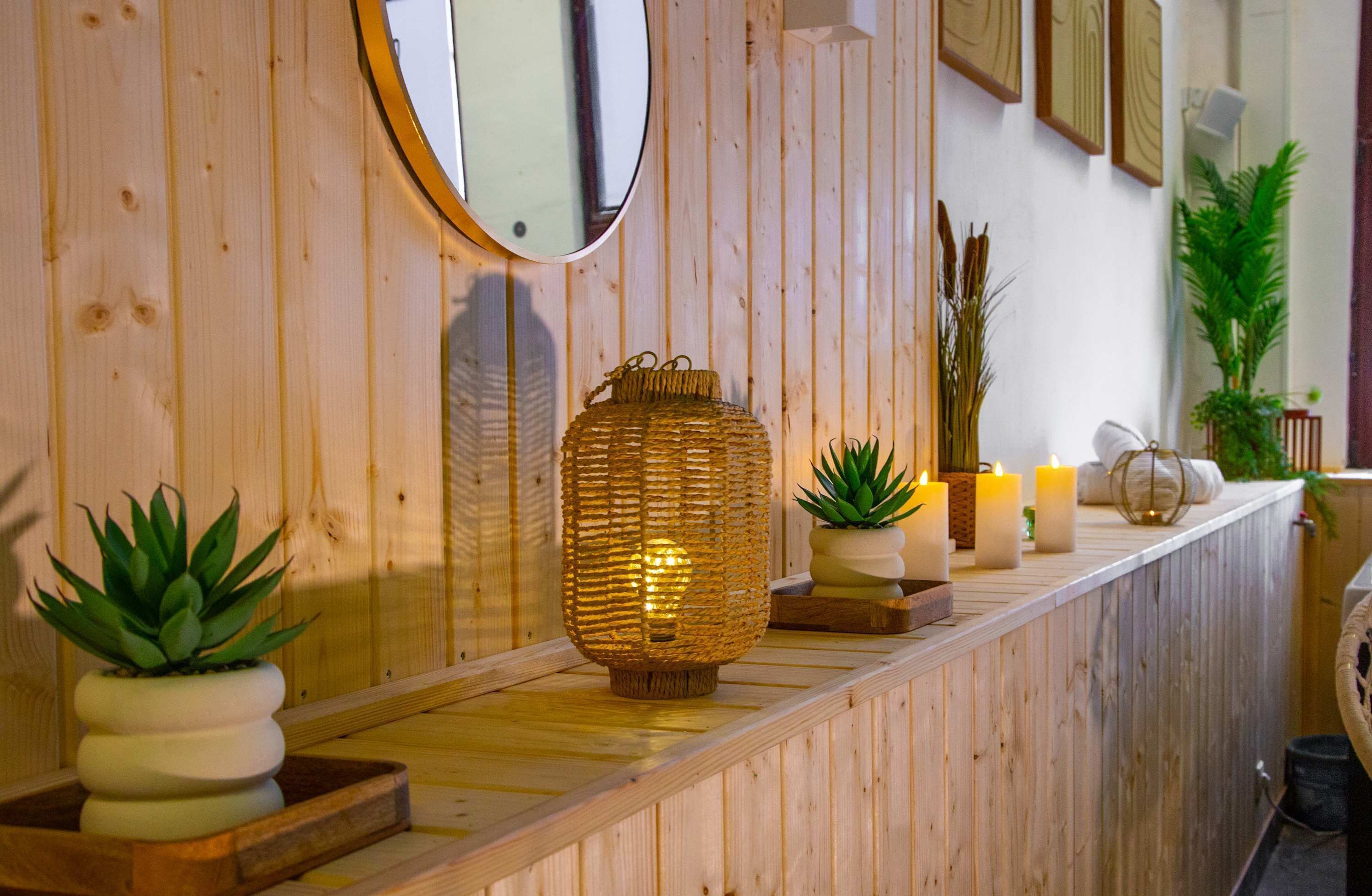 Un comptoir d’accueil en bois agrémenté d’un miroir, de bougies et de plantes en pot.