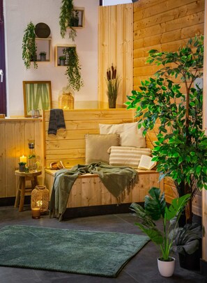 A cozy room with a wooden bed, a green rug, a potted plant, and a small table with a candle and a bottle. - Casino Whirlpool-sauna-kino-indoor-basketball (Hoehr-Grenzhausen)