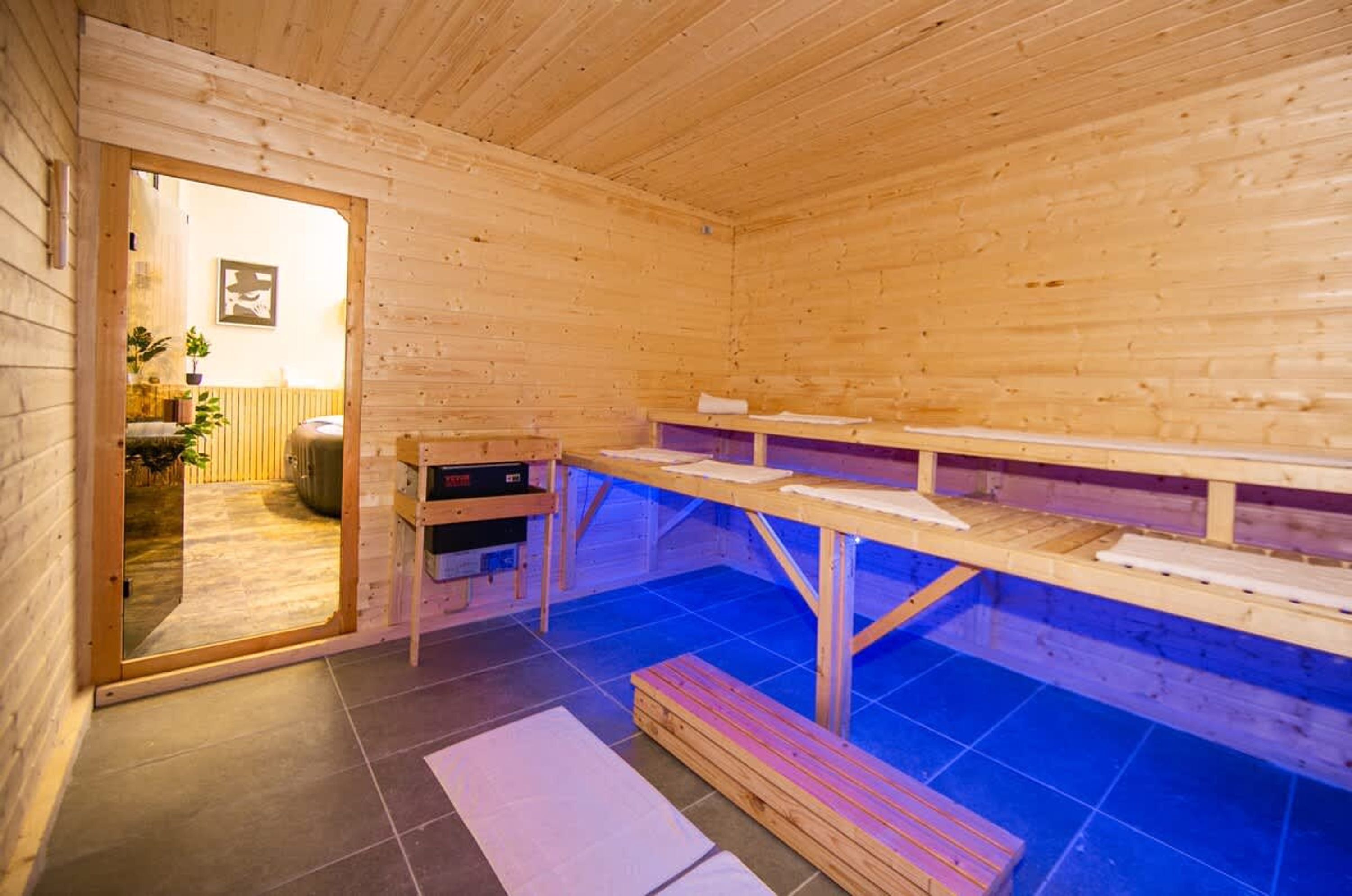 Et saunaområde med trævægge og bænke, en trædør og et fliset gulv.