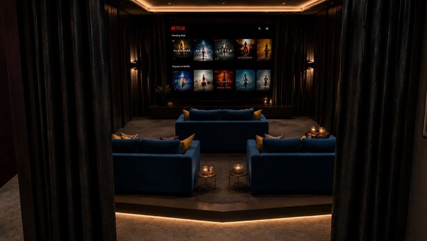 A dark room with a Netflix screen displaying movie options, two blue sofas, and a small table with candles. - Besto Residence Kino-billard-poker-kicker (Albstadt)