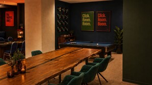 A room with a pool table, green chairs, a wooden table, and two framed signs on the wall. - Besto Residence Kino-billard-poker-kicker (Albstadt)