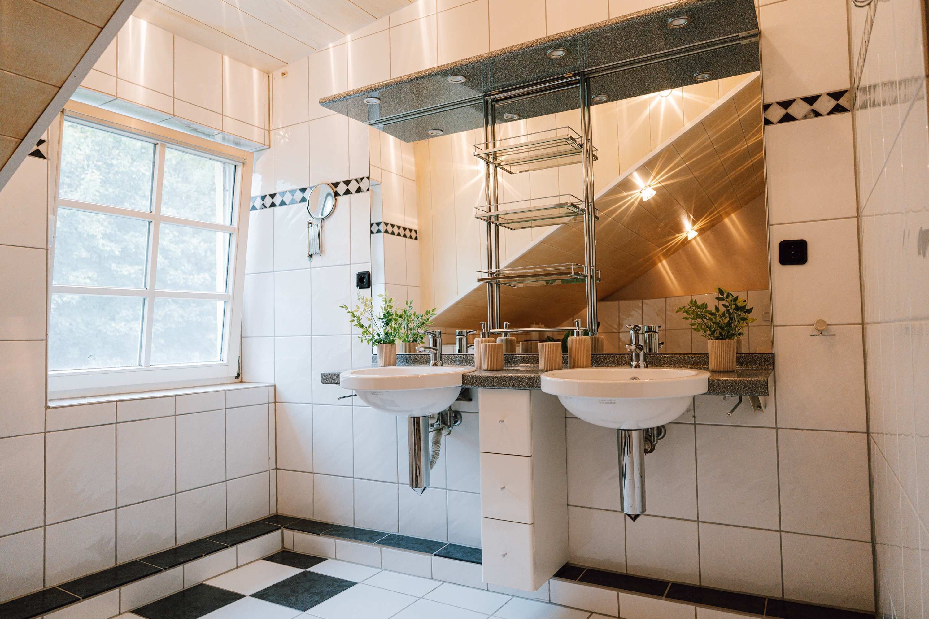 A bathroom with two sinks, a window, and a mirror with a towel rack.