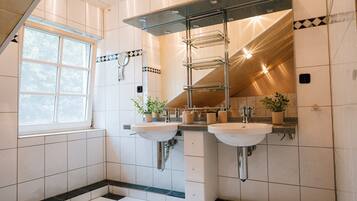 A bathroom with two sinks, a window, and a mirror with a towel rack.