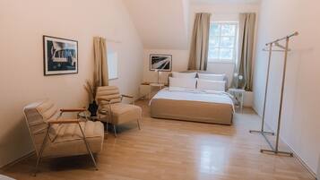 Un dormitorio con una cama, una silla, una mesita de noche, una lámpara de pie y una ventana con cortinas.