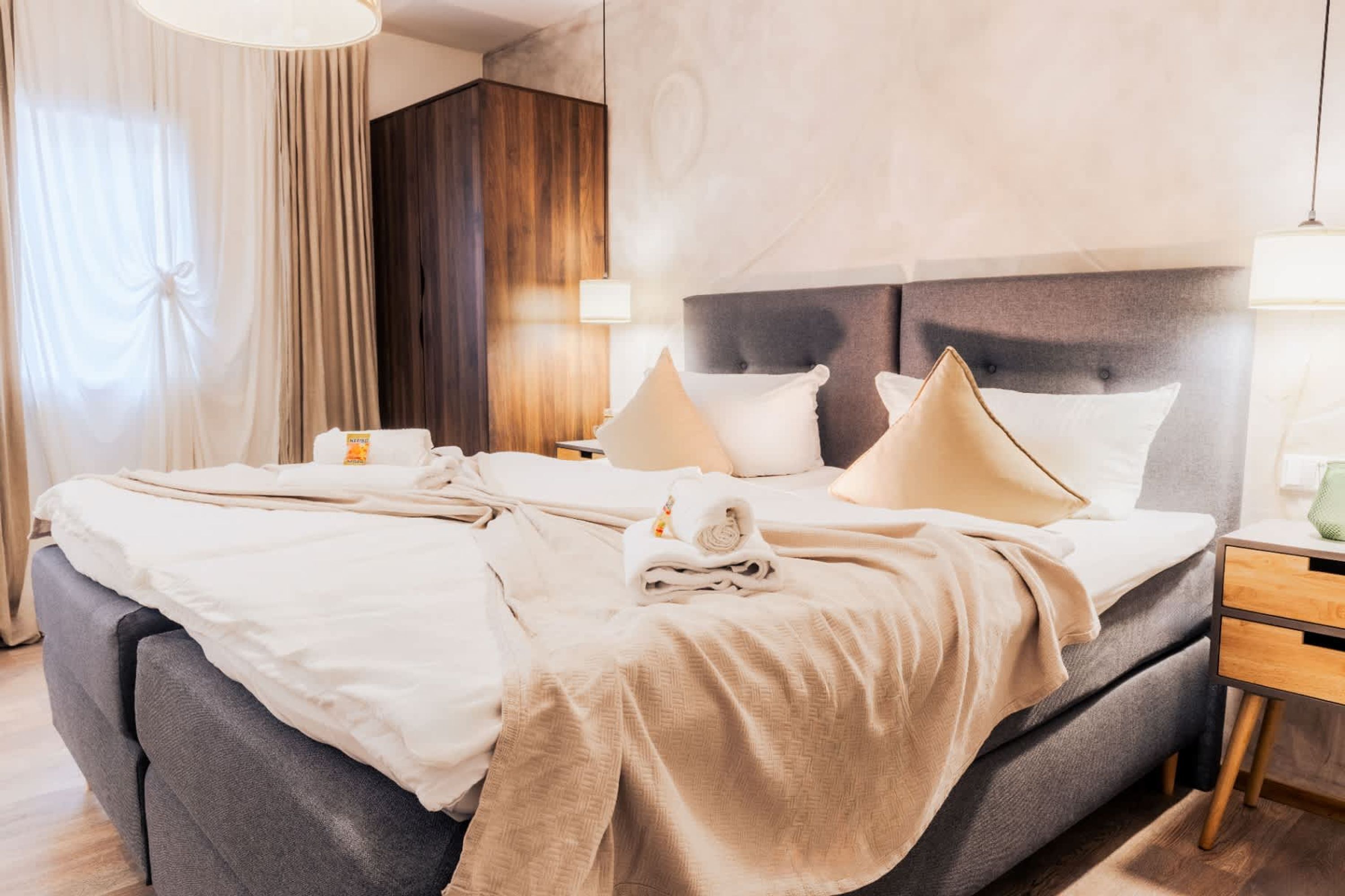 Camera d'albergo con un letto grande, un comodino, una lampada e vista sull'esterno.