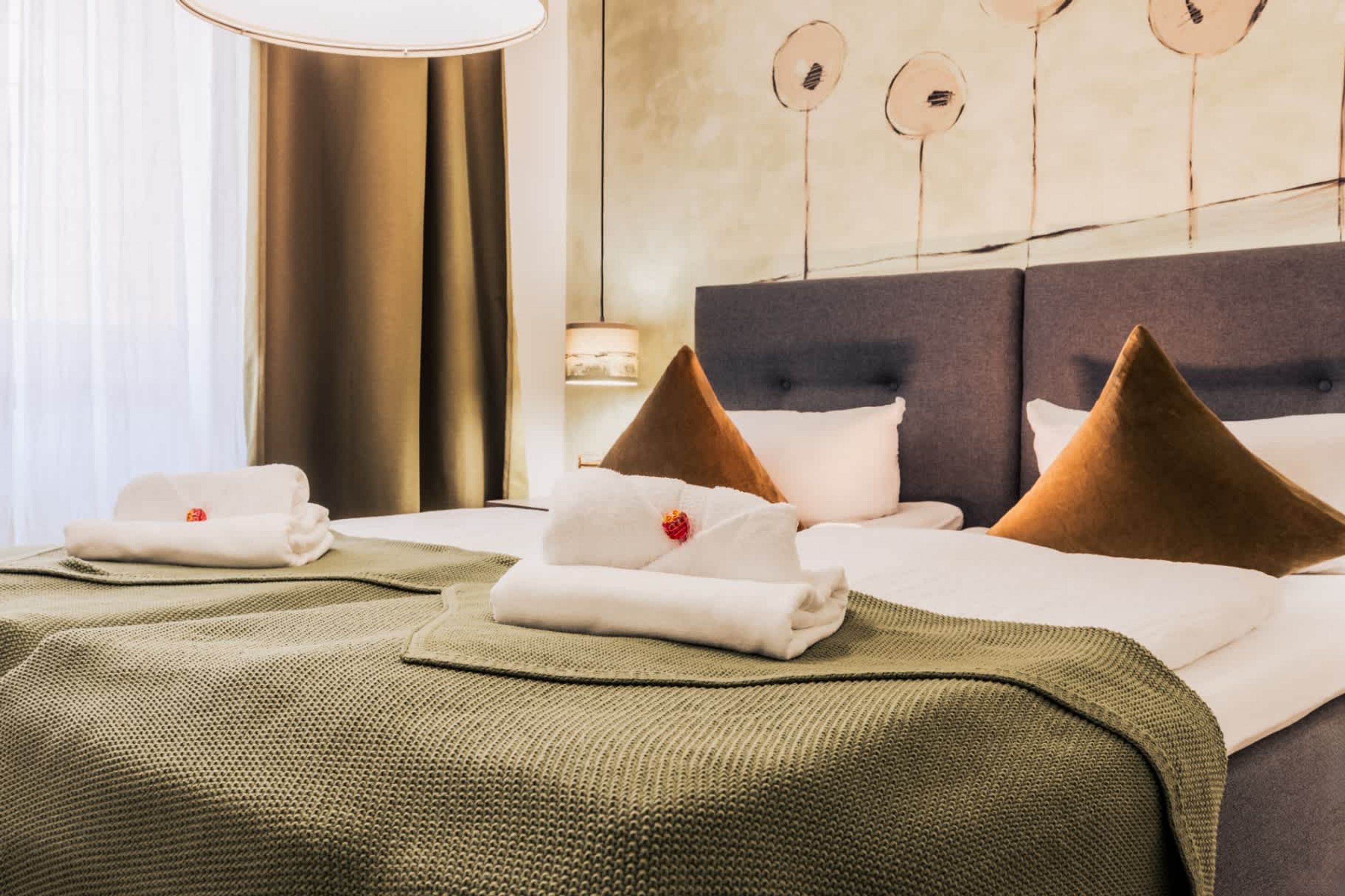 Ein Hotelzimmer mit Bett, Kissen, Decke und einer Wand mit runden Verzierungen.