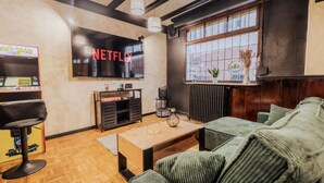 Una sala de estar con un sofá verde, una mesa de centro de madera y una pantalla de televisión que muestra 'NETFLIX'.