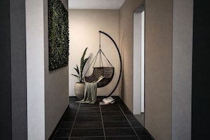A hallway with a hanging chair, a potted plant, and a wall-mounted green wall. - Brauhaus Bueckeburg Sauna-whirlpool-villa (Bueckeburg)