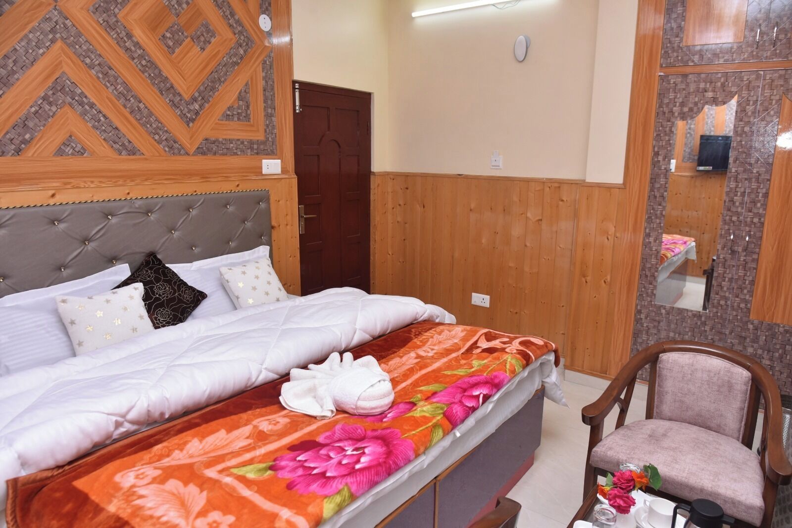 A bedroom with a bed, a wooden headboard, a mirror, and a chair.