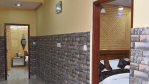 A hotel corridor with a brick-patterned wall, a wooden door frame, and a bed with a patterned headboard. - Sarahan Holliday Inn (Rampur)
