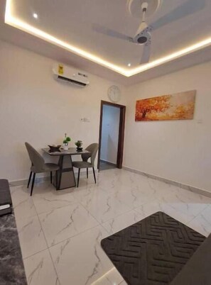Un espace repas comprenant une table et des chaises, un ventilateur de plafond, un appareil de climatisation et une porte.