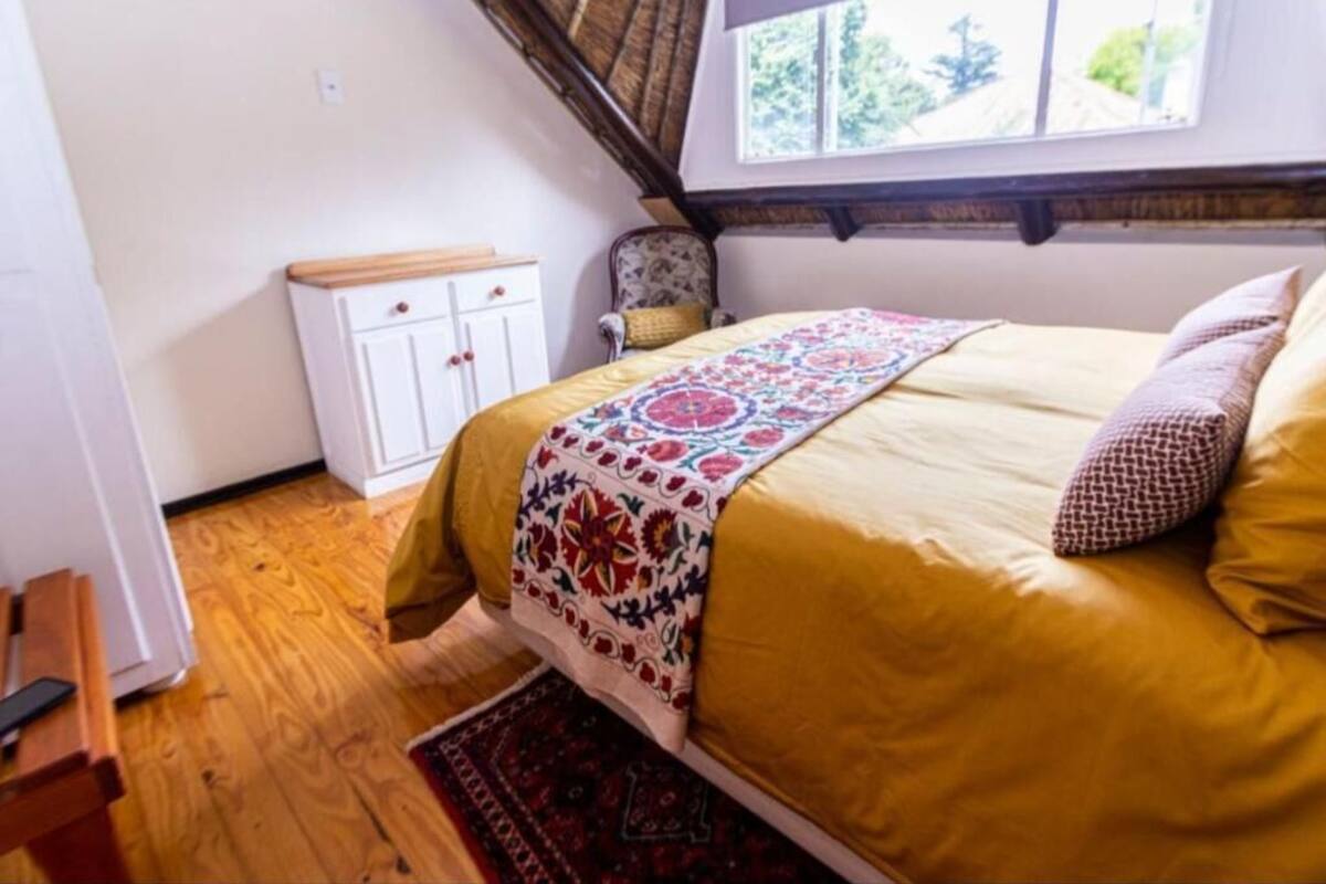 A bedroom with a bed, a window, a wardrobe, and a chair.