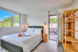 Habitación de hotel con cama, armario de madera, balcón y vistas, además de una ventana.
